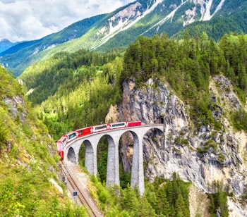 Det røde Gletsjer-ekspres tog krydser den historiske Landwasser Viadukt i de schweiziske alper med betagende bjergudsigt