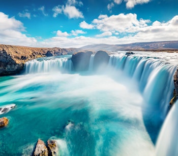 Imponerende Godafoss vandfald i Island med brusende vand over 12 meter høj klippe omgivet af betagende islandsk natur