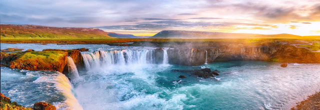 Betagende solopgang over Godafoss-vandfaldet i Island med gyldent lys der oplyser det turkise vand og den dramatiske himmel
