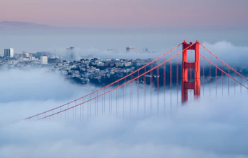 Golden Gate Bridge i morgentåge med San Francisco skyline i baggrunden