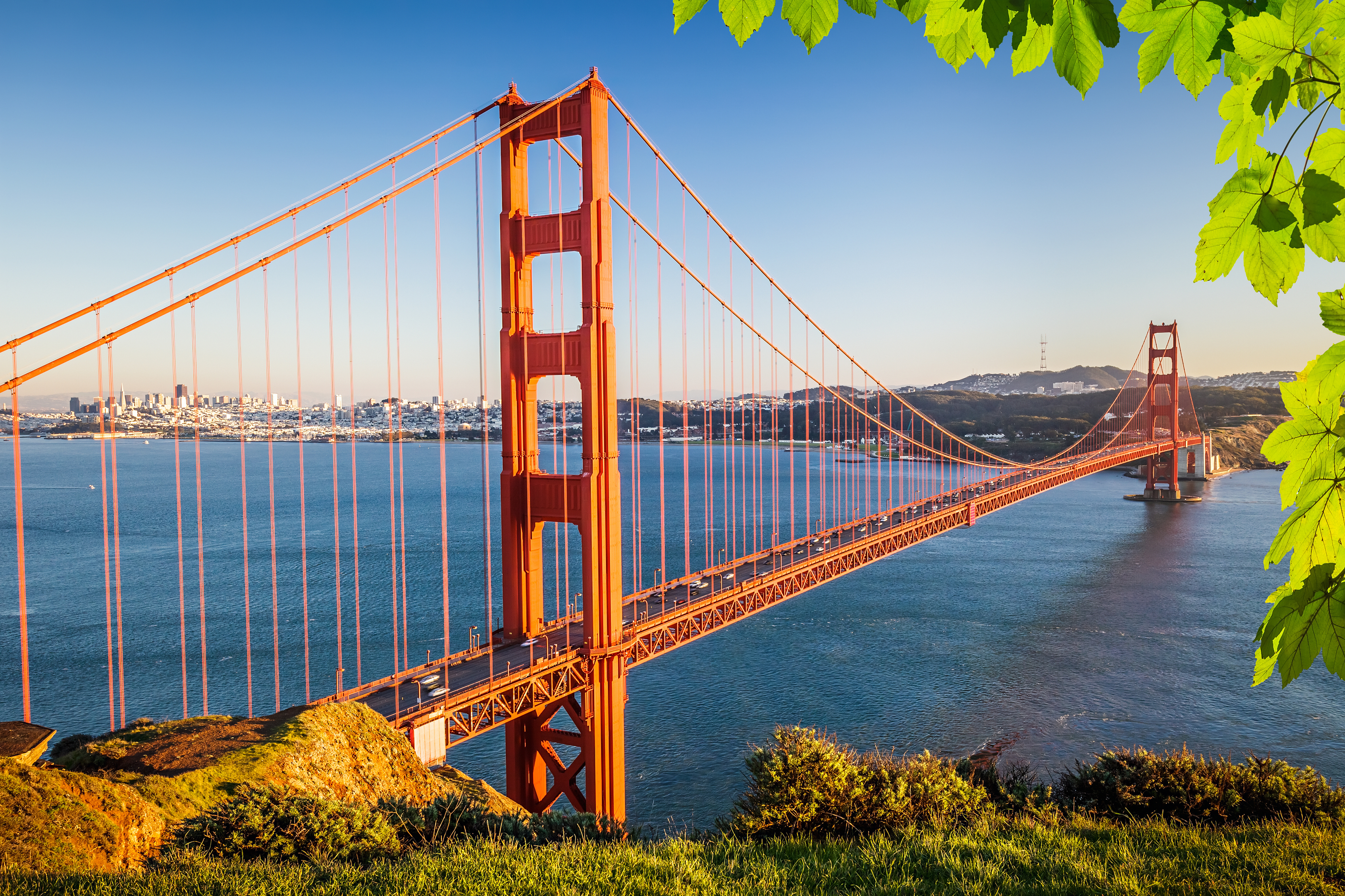 Golden Gate broen i San Francisco ved solnedgang med blåt vand og byens skyline