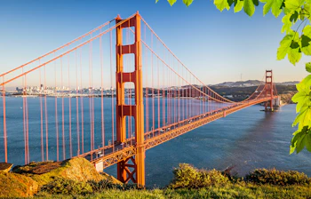 Golden Gate broen i San Francisco ved solnedgang med blåt vand og byens skyline