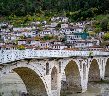 Den historiske Gorica-bro oplyst i aftenlys forbinder bydelene i UNESCO-byen Berat i Albanien