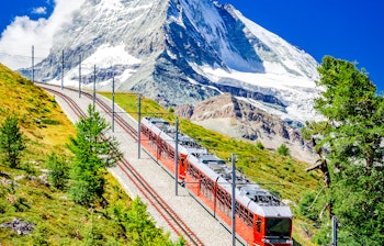 Rødt tandhjulstog på Gornergratbahn kører mod Matterhorn i de schweiziske alper nær Zermatt med storslået bjergpanorama