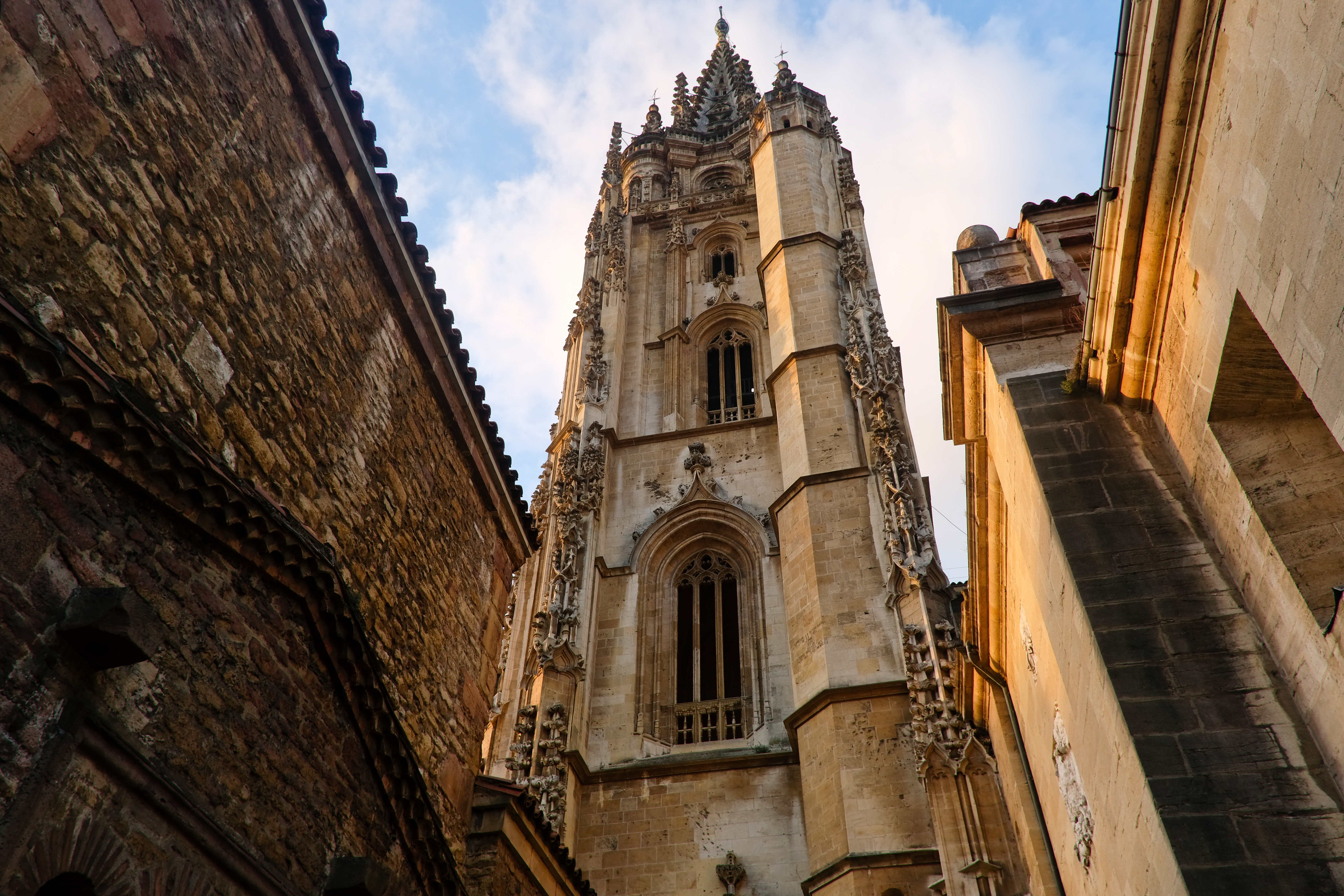 Gotisk katedral med høj spir i historisk spansk by med middelalderlige bygninger