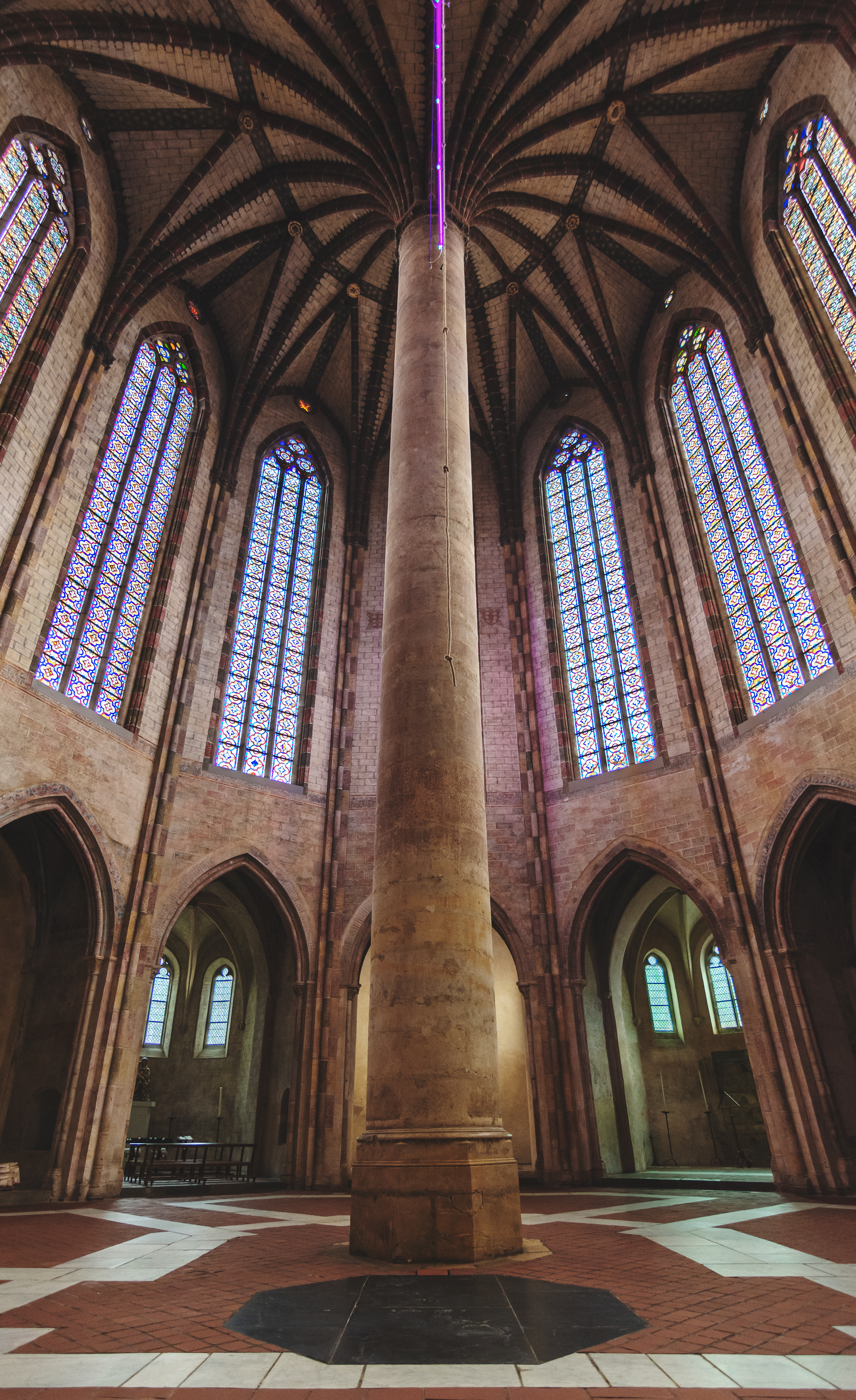 Imponerende interiør i Jakobinerkirken i Toulouse med høje søjler, gotiske hvælvinger og farverige glasmosaikvinduer