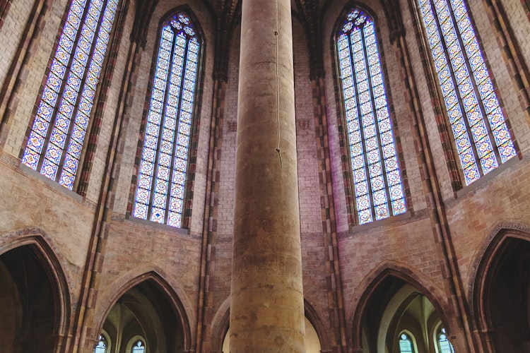 Imponerende interiør i Jakobinerkirken i Toulouse med høje søjler, gotiske hvælvinger og farverige glasmosaikvinduer