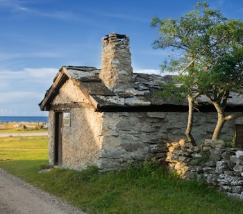 Traditionelt svensk stenhus med skorsten på Gotlands kyst ved solopgang