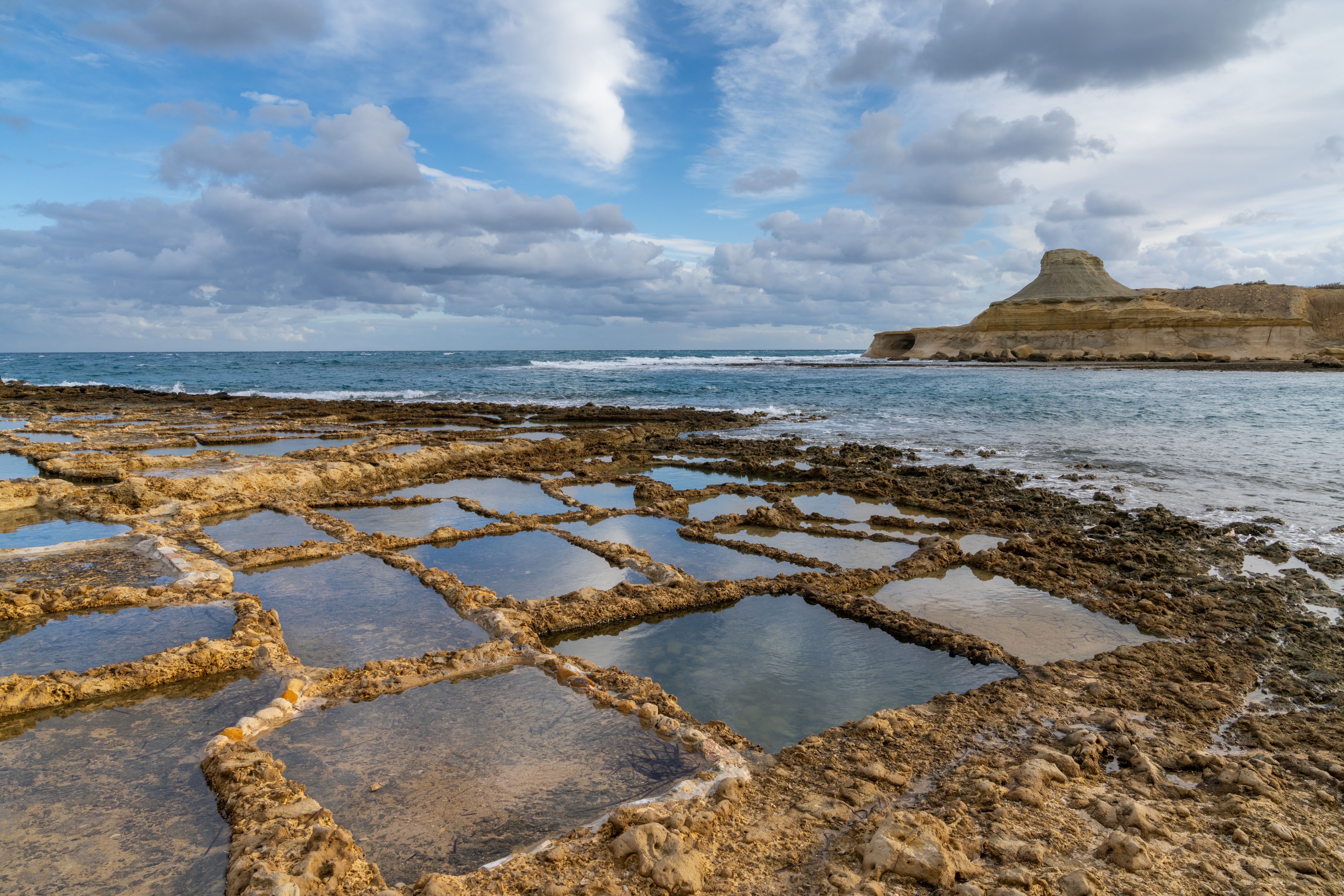 Traditionelle saltpander ved Xwejni Bay på Gozo øen Malta med middelhavsudsigt og kalkstensformationer