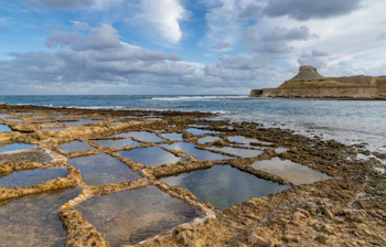 Traditionelle saltpander ved Xwejni Bay på Gozo øen Malta med middelhavsudsigt og kalkstensformationer