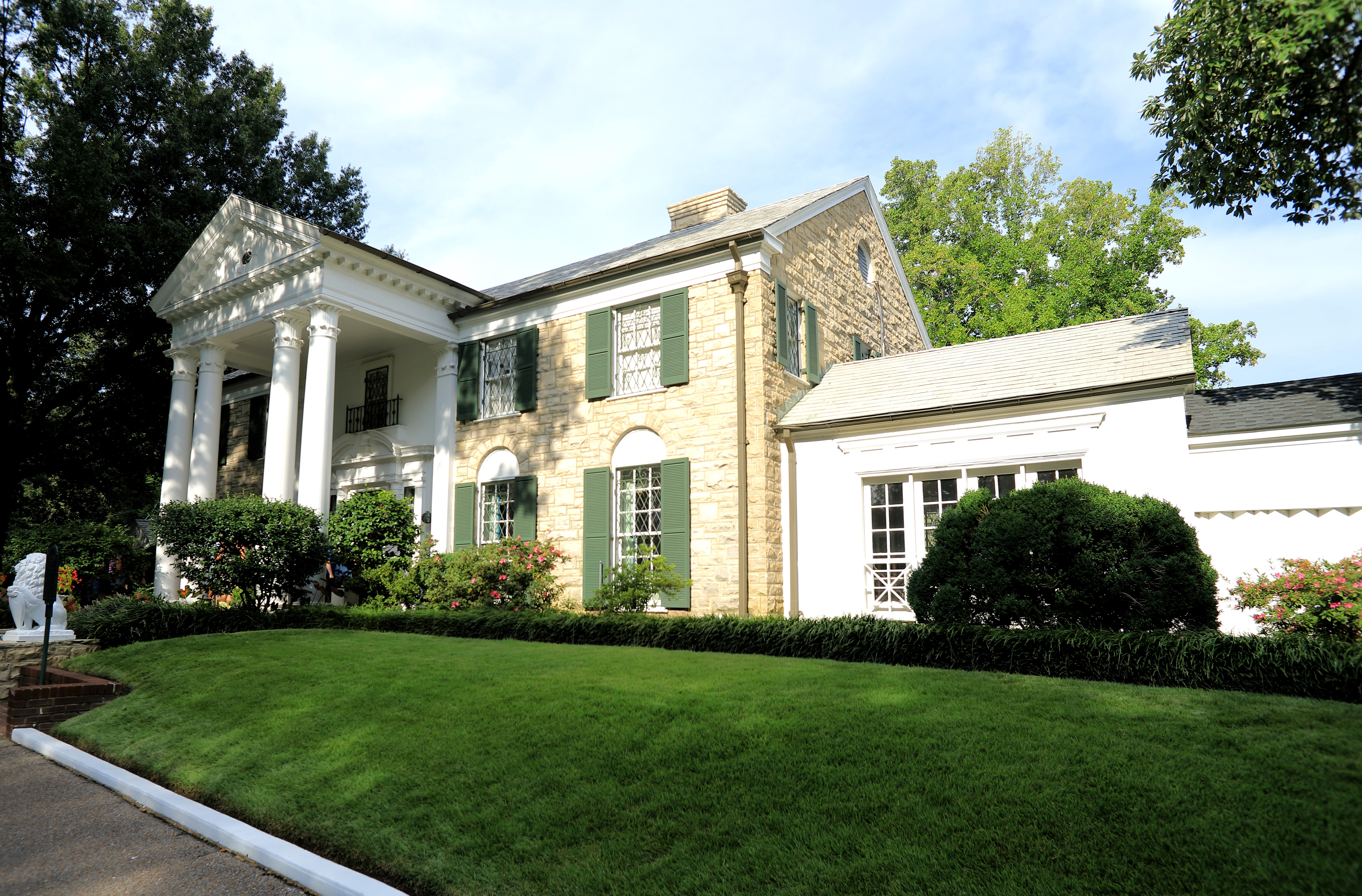 Graceland i Memphis, Tennessee – Elvis Presleys berømte hjem med hvide søjler og grønne skodder omgivet af grøn græsplæne