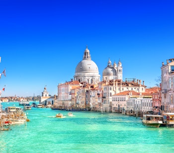 Panoramaudsigt over Grand Canal med den majestætiske Basilica Santa Maria della Salute i Venedig under blå himmel