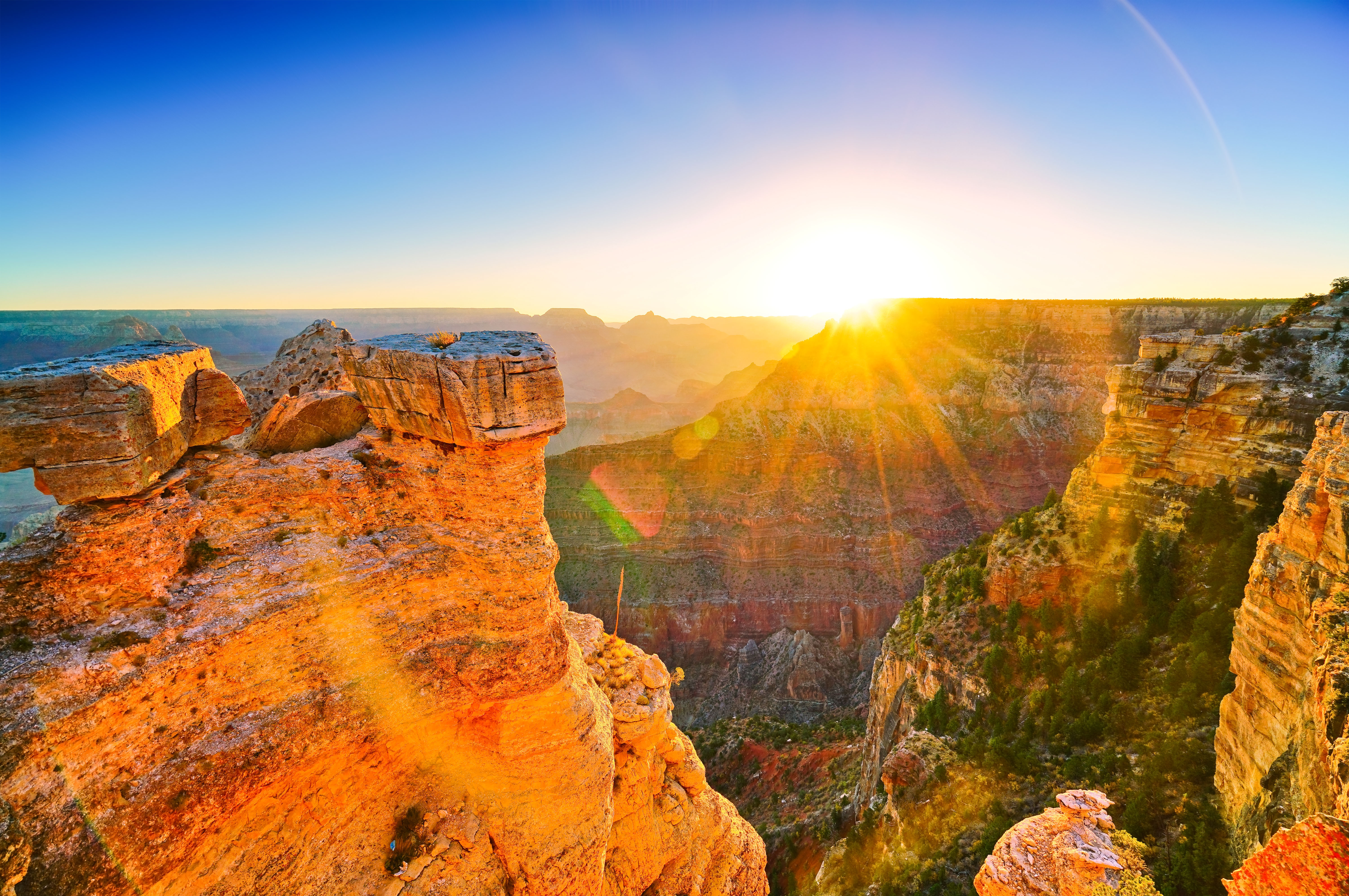 Spektakulær solnedgang over Grand Canyon med gyldent lys på røde klippeformationer i Arizona