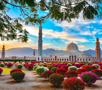 Betagende morgenvy af Grand Moskeen i Muscat, Omans mest ikoniske religiøse bygningsværk badet i solopgangens gyldne lys