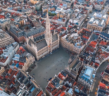 Luftfoto af Grand Place pladsen i Bruxelles med det historiske rådhus og farverige bygninger i solnedgangslys