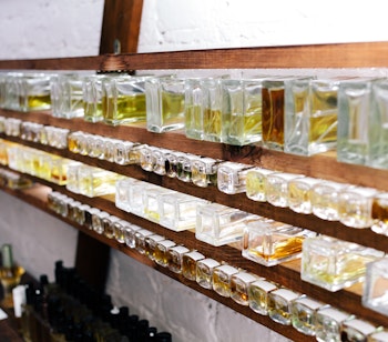 Historisk parfumelaboratorium hos Fragonard i Grasse med farverige glasflasker udstillet på træhylder, der viser traditionel fransk parfumeproduktion