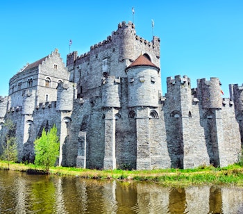 Det historiske Gravensteen slot fra middelalderen spejler sig i kanalvandet i den charmerende by Gent i Belgien