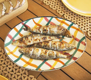 Grillede sardiner på farverig portugisisk tallerken med traditionel middelhavsmad