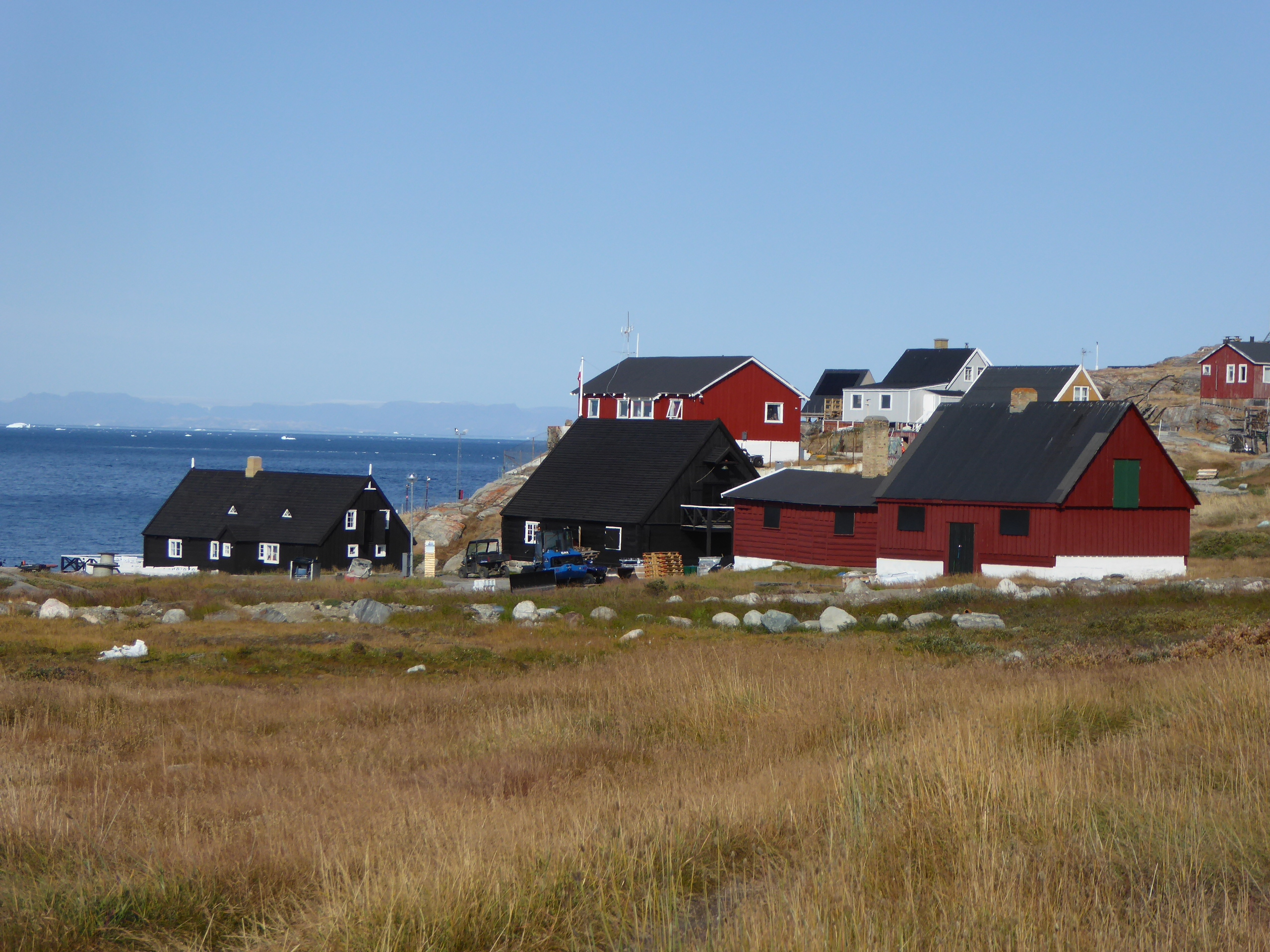 Traditionel inuit landsby med farverige træhuse langs Grønlands kyst