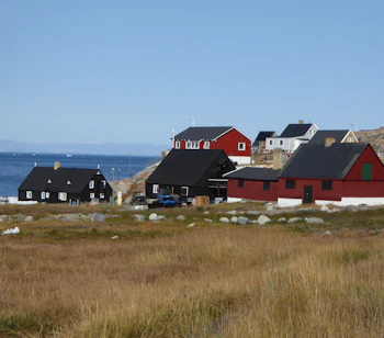 Traditionel inuit landsby med farverige træhuse langs Grønlands kyst