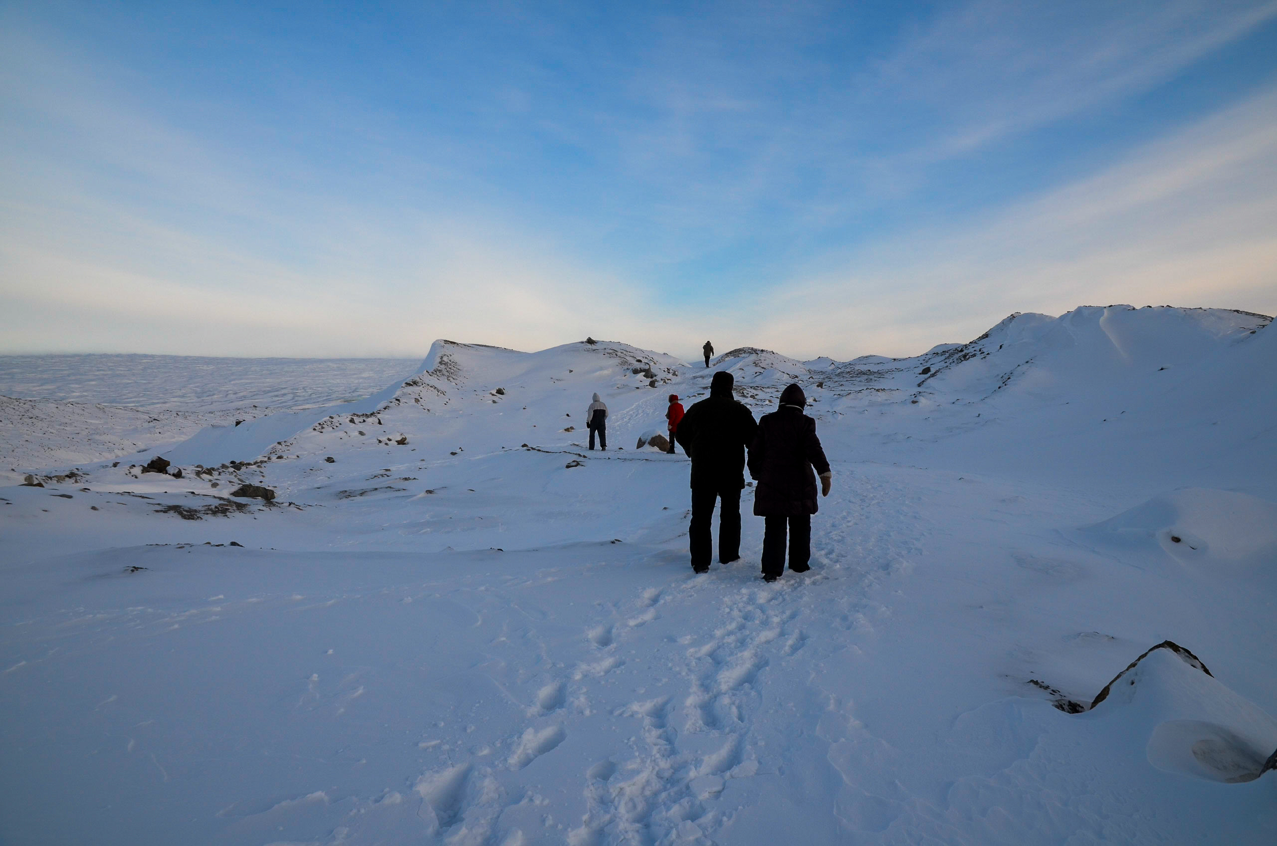 Gruppe af vintervandrer på trekking tur gennem snedækket arktisk landskab i Grønland med bjerge