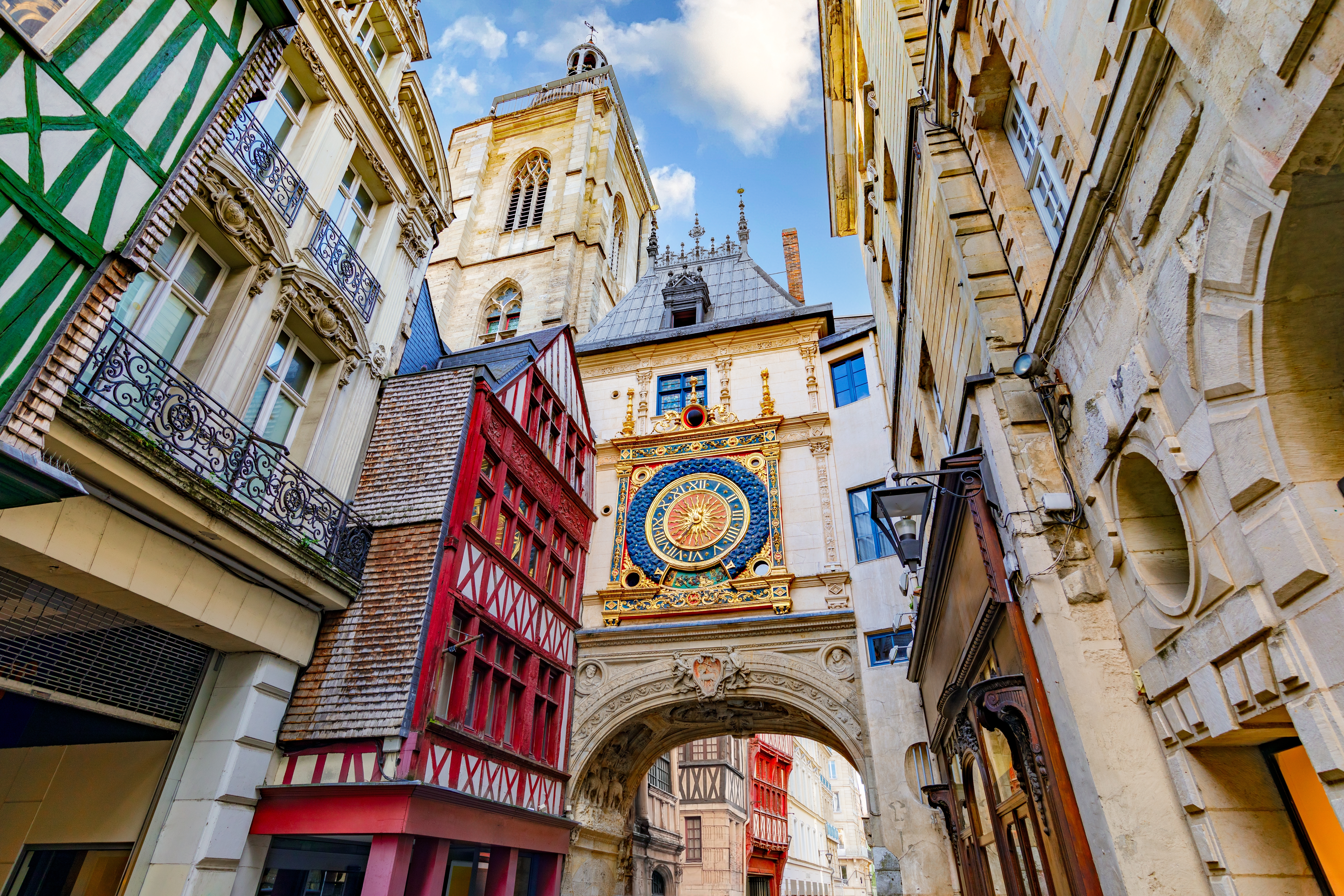 Den berømte Gros-Horloge renæssance-ur i Rouen, Normandiet, der danner en portal over en brostensbelagt gågade med traditionelle bindingsværkshuse og blå himmel