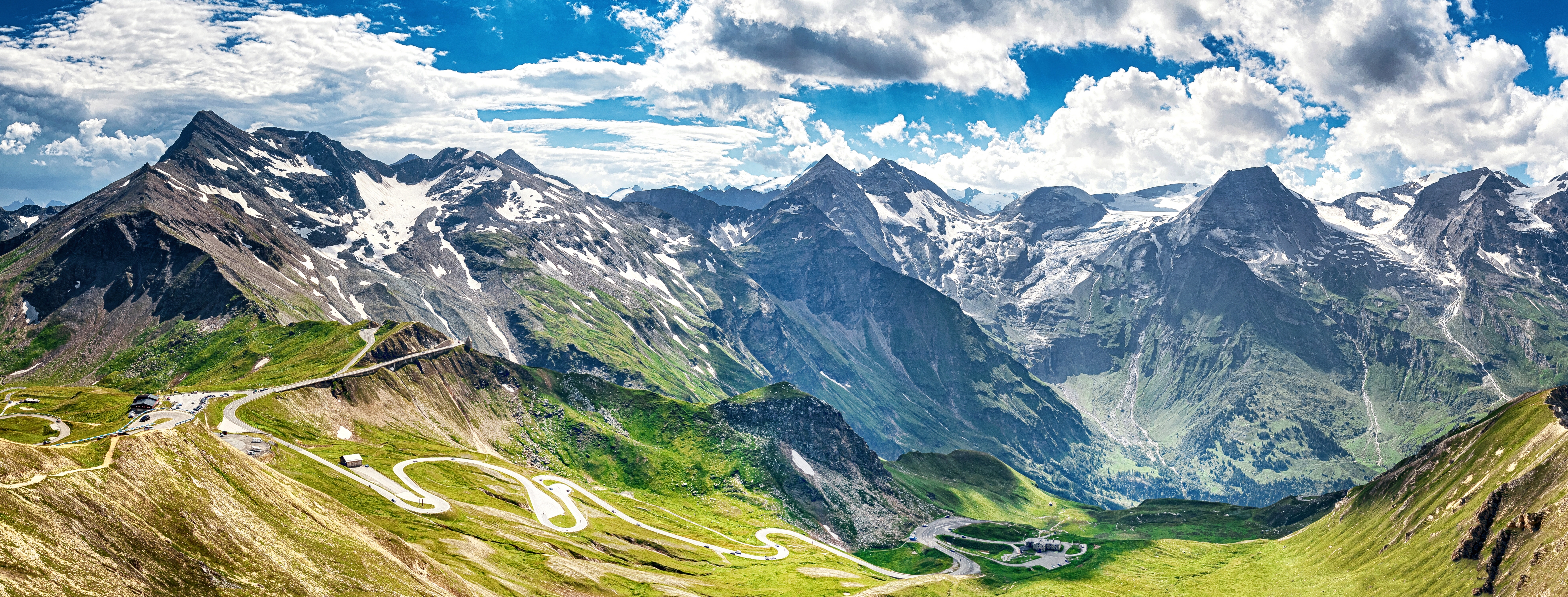 Betagende panoramaudsigt over Grossglockner Højalpine Vej, der snor sig gennem de østrigske alper med majestætiske bjergtinder og grønne dale i Hohe Tauern Nationalpark