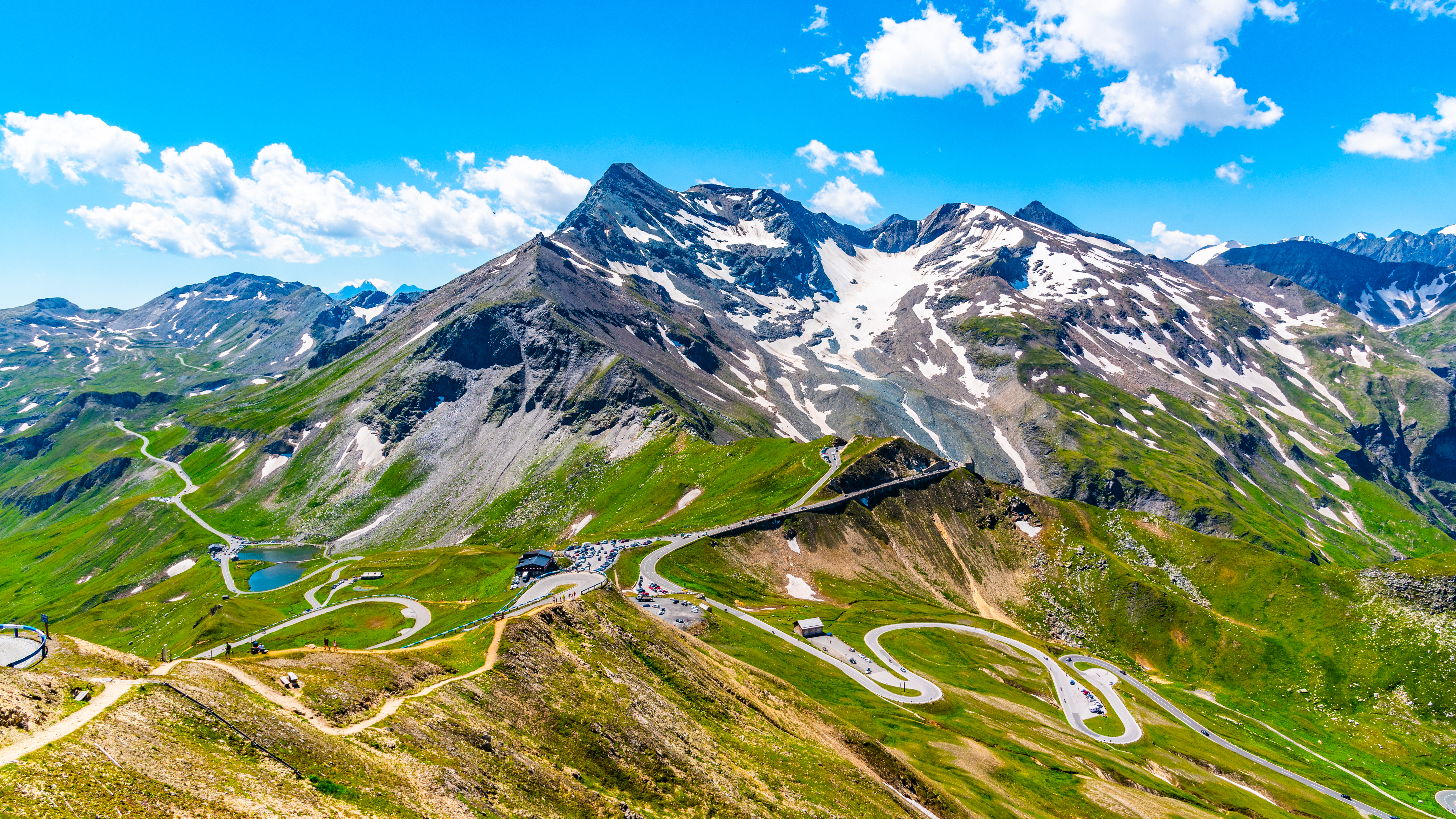 Spektakulær udsigt over Grossglockner Højalpevej med skarpe hårnålesving gennem grønne enge i de østrigske alper