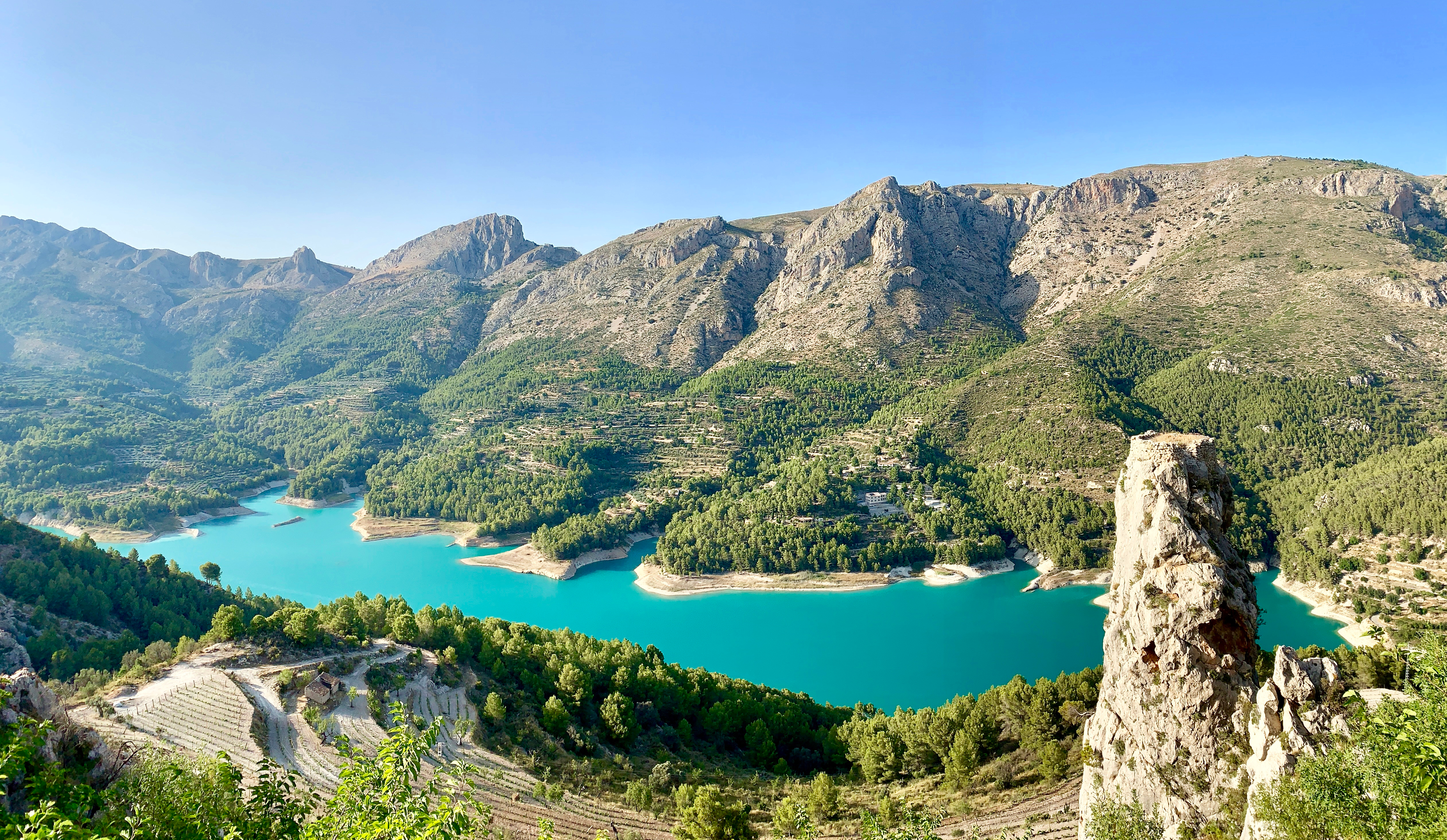 Betagende panoramaudsigt over Guadalest-reservoiret med krystalklart vand og den historiske bjerglandsby med middelalderborg i Alicante, Spanien