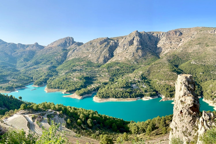 Betagende panoramaudsigt over Guadalest-reservoiret med krystalklart vand og den historiske bjerglandsby med middelalderborg i Alicante, Spanien