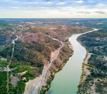 Luftfoto af den smukke Guadiana-flod der slynger sig gennem det grønne bakkede landskab i Alentejo-regionen i Portugal