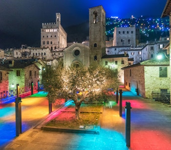 Den charmerende middelalderby Gubbio i aftenlys med oplyste historiske stenbygninger, smalle gader og det imponerende Palazzo dei Consoli i Umbrien, Italien