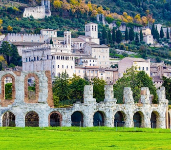 Det imponerende 2000 år gamle romerske amfiteater og det majestætiske renæssancepalads i den historiske bjergby Gubbio i Umbrien på en klar vinterdag