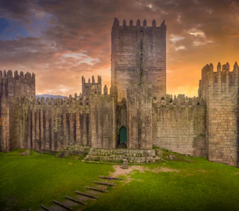 Middelalderborg Guimarães Slot med dramatisk solnedgang i det nordlige Portugal