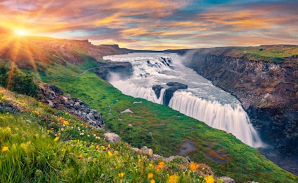 Betagende solopgang over det mægtige Gullfoss-vandfald i Island, hvor det gyldne morgenlys oplyser Hvítá-flodens kaskader der styrter ned i en dramatisk kløft