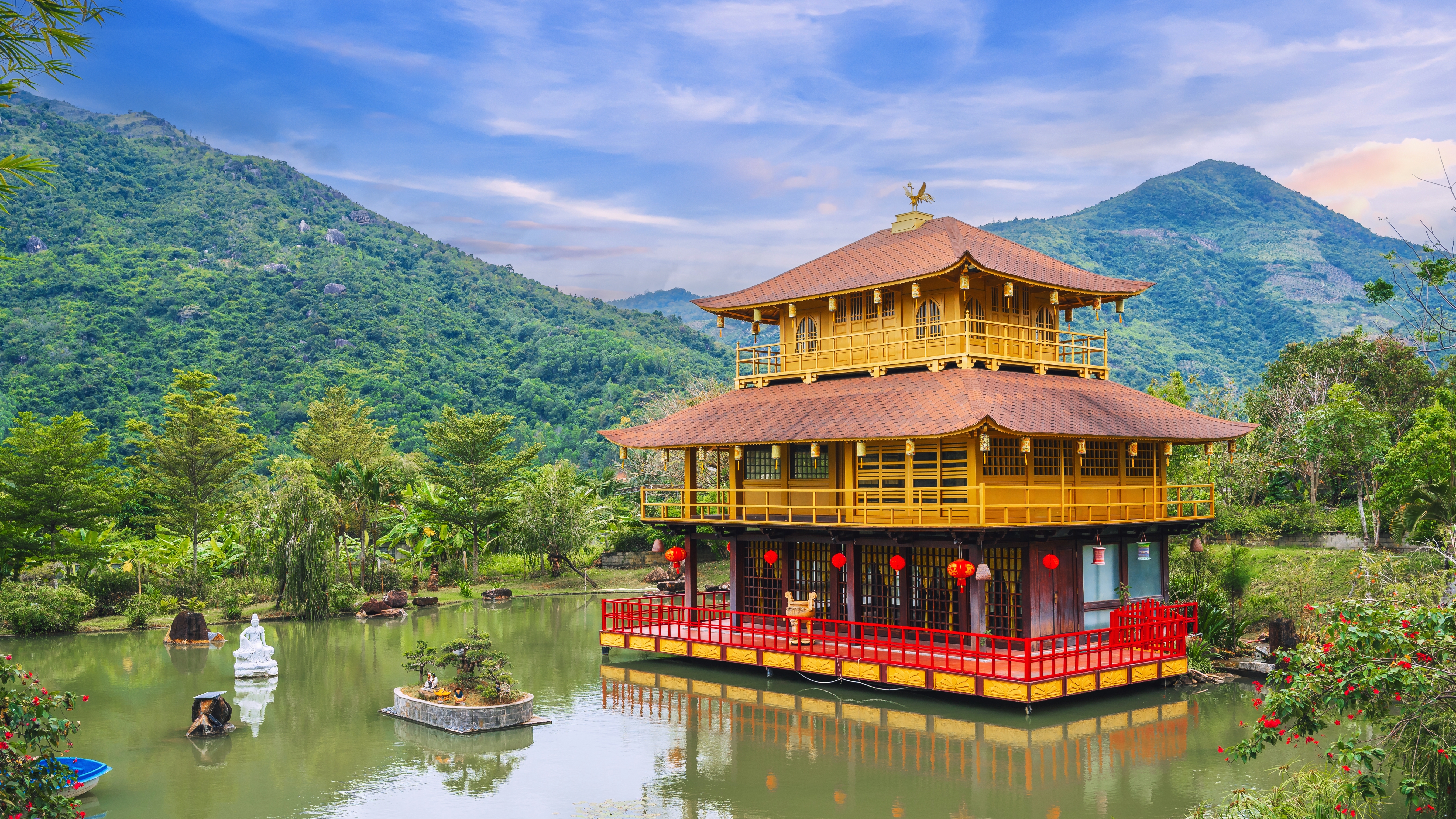 Smukt gyldent pagode-tempel bygget på en fredfyldt sø omgivet af grønne bjerge i Nha Trang, Vietnam