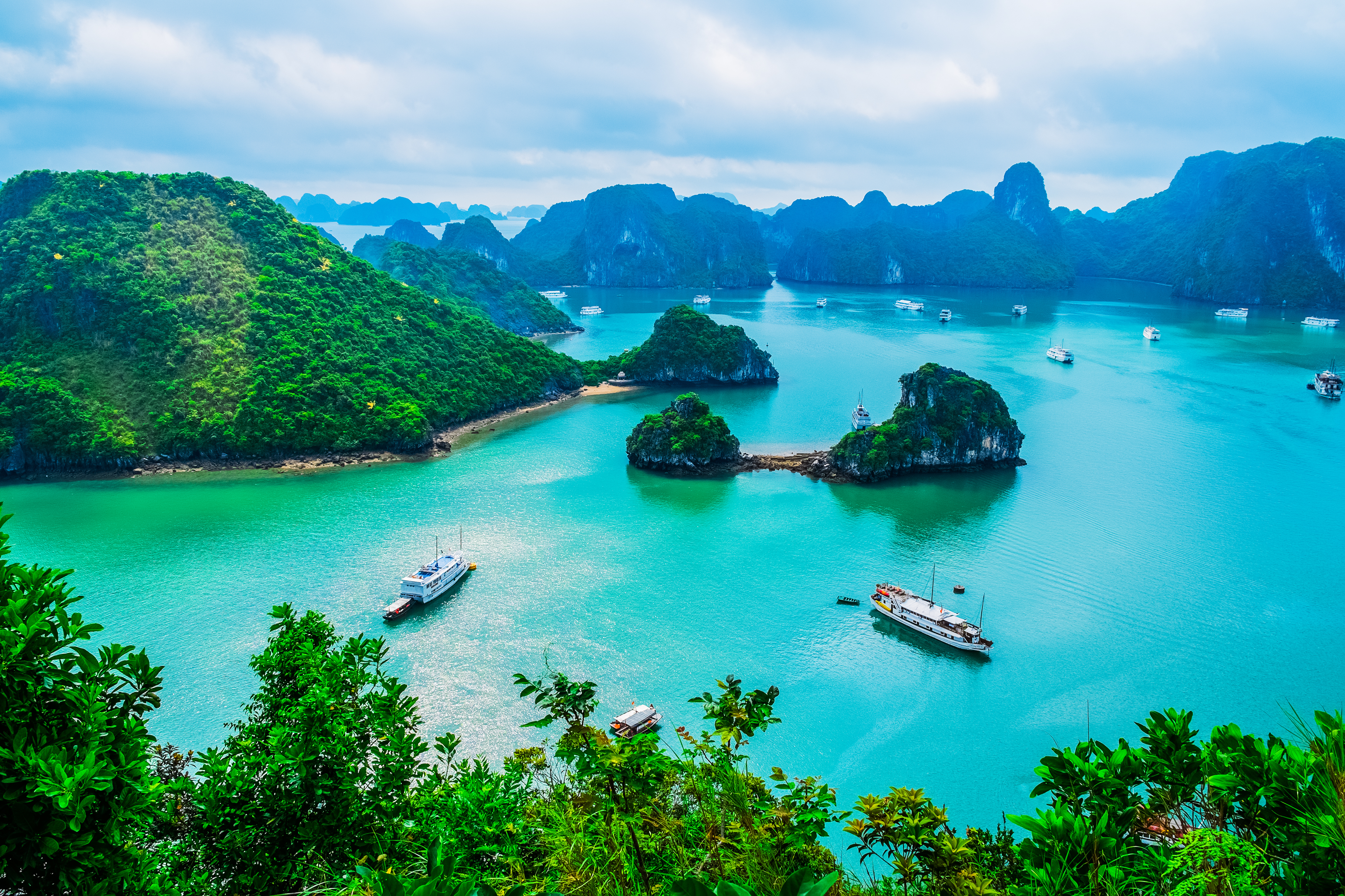 Spektakulær udsigt over Ha Long Bay i Vietnam med smaragdgrønt vand, kalkstensøer og turistbåde
