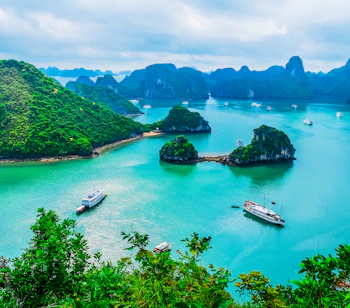 Spektakulær udsigt over Ha Long Bay i Vietnam med smaragdgrønt vand, kalkstensøer og turistbåde