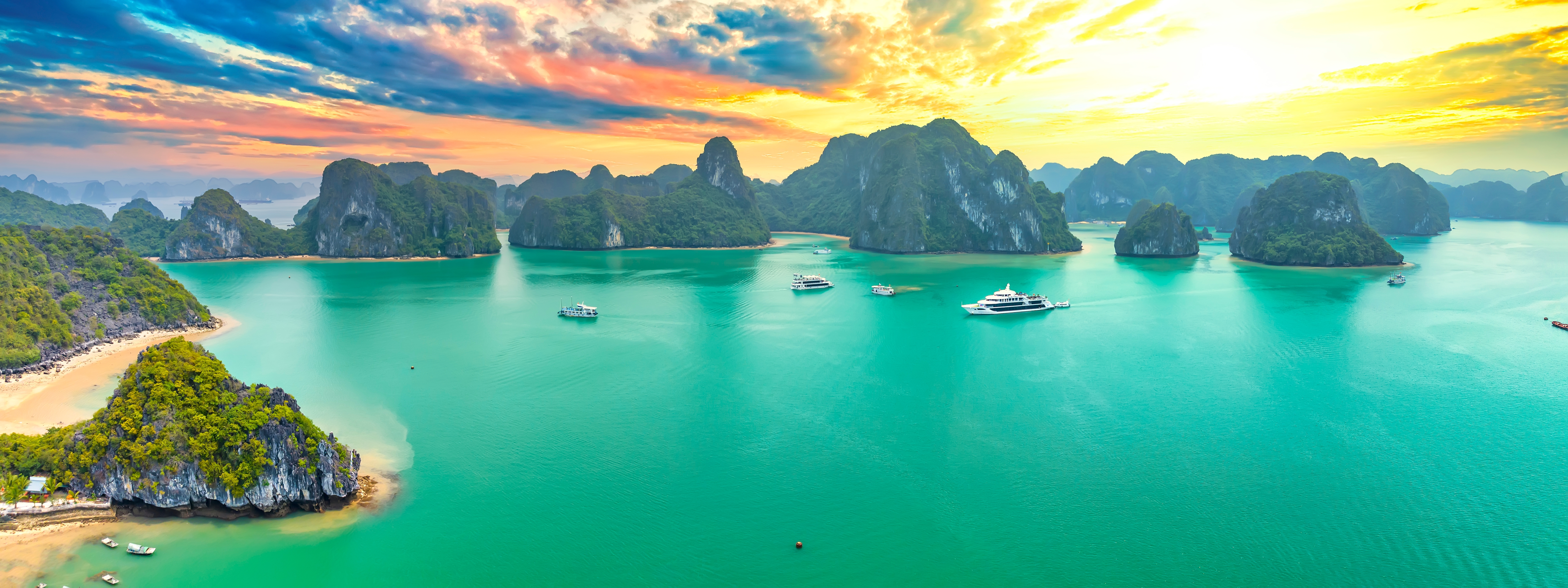 Spektakulær solnedgang over Ha Long Bay i Vietnam med kalkstensklipper og krydstogtsbåde