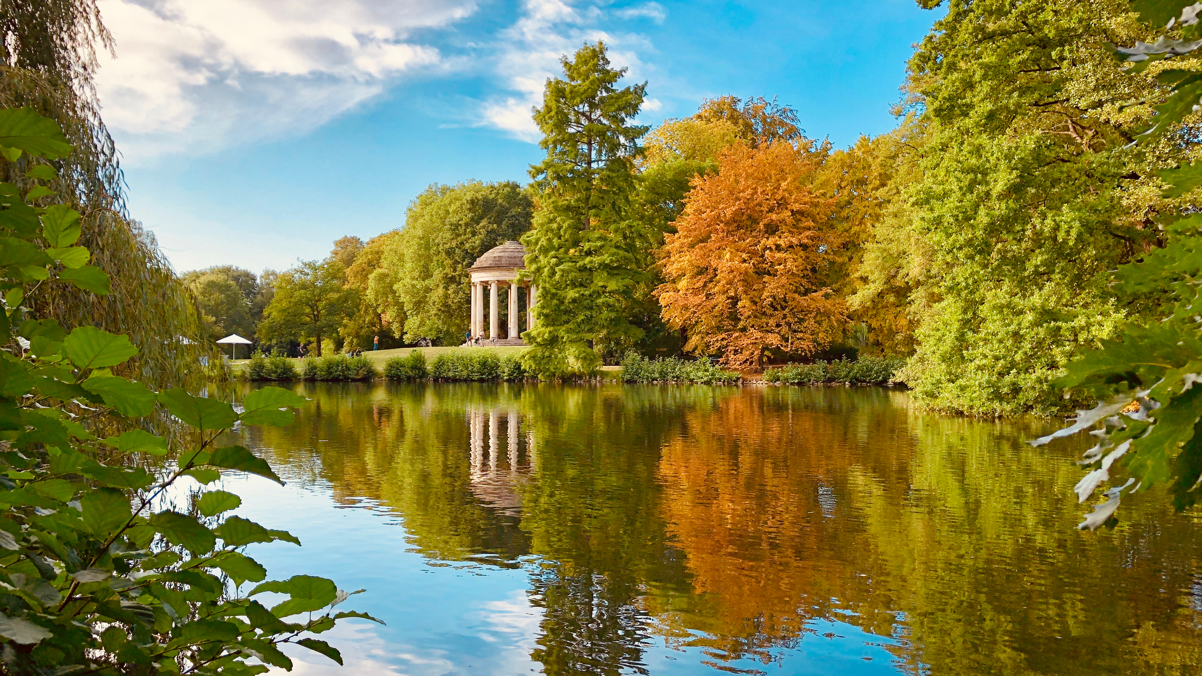 Smuk efterårsudsigt over Hannover med farverige træer der spejler sig i søen under blå himmel