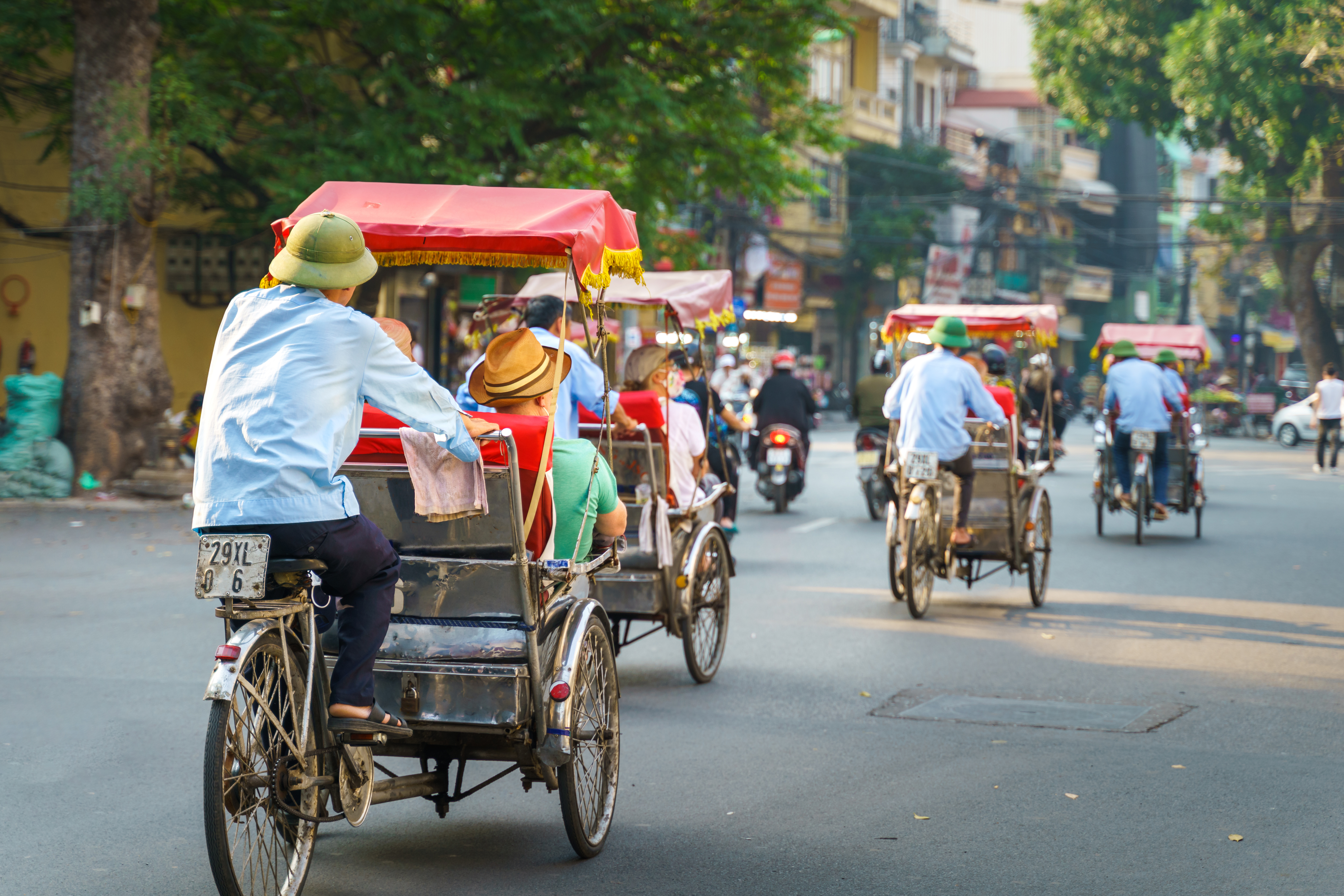 Traditionel cyclo rickshaw-tur gennem travle gader i Hanoi, Vietnam med turister