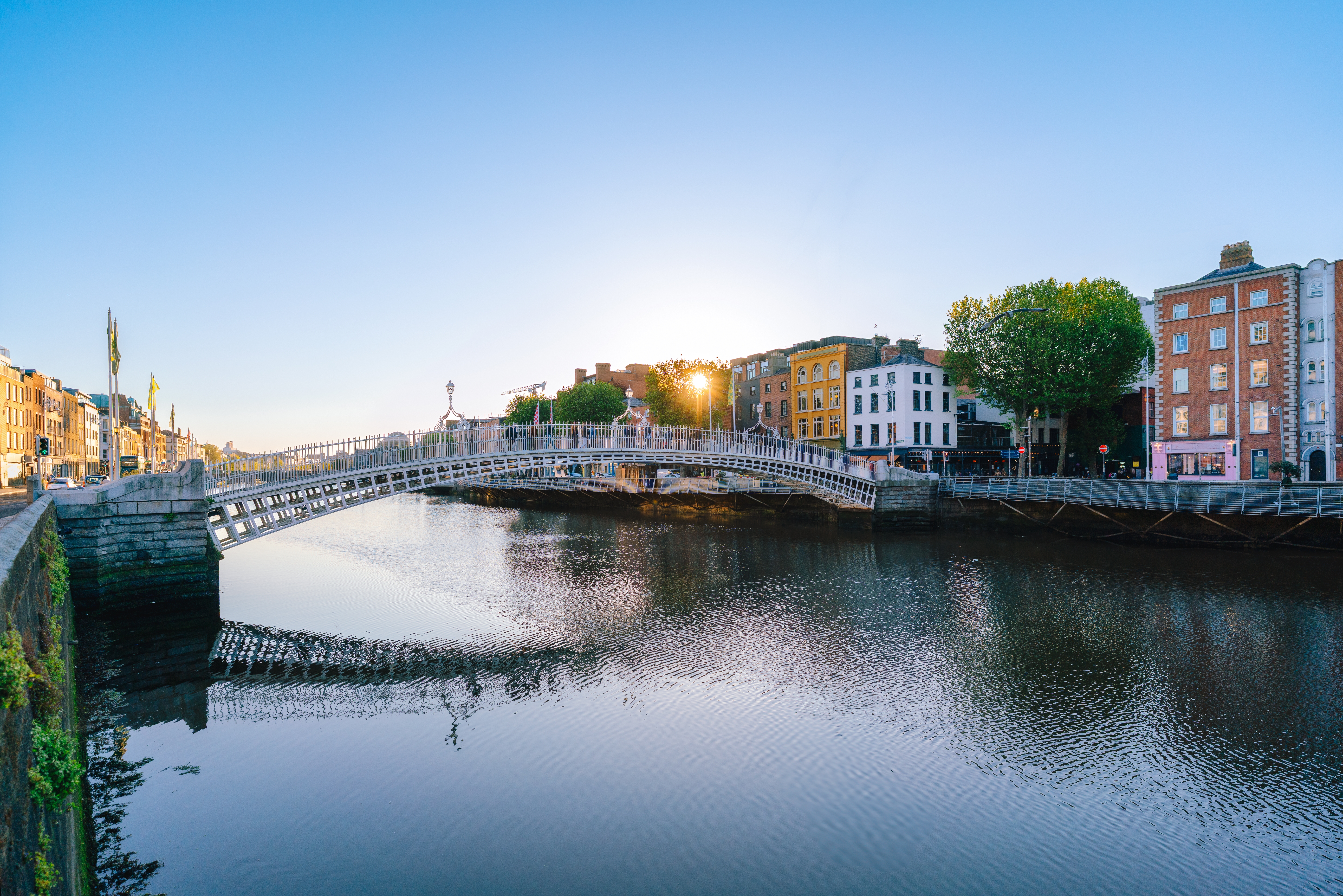 Ha'penny Bridge over River Liffey i Dublin ved solnedgang med farverige bygninger