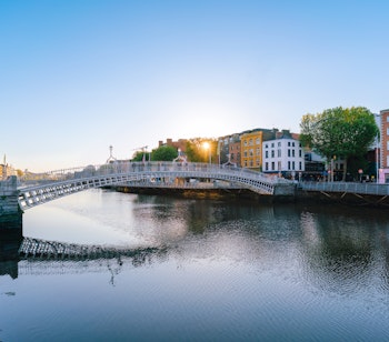 Ha'penny Bridge over River Liffey i Dublin ved solnedgang med farverige bygninger