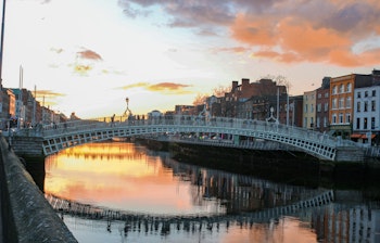 Den ikoniske Ha'penny bro oplyst om aftenen over Liffey-floden i Dublin, Irland - et must-see når du besøger den irske hovedstad