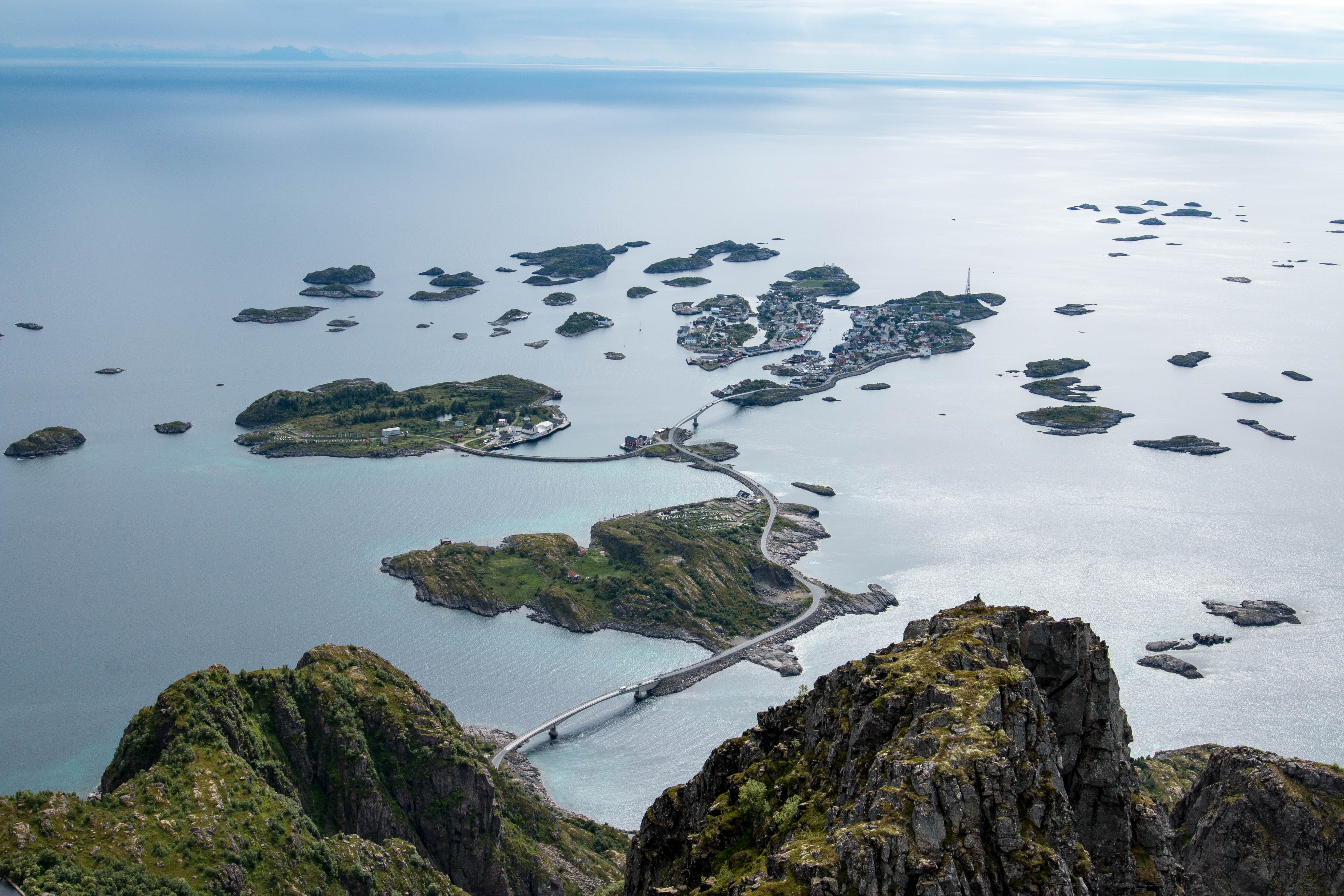 Luftfoto af Henningsvær fiskerleje på Lofoten i Norge, omgivet af roligt blåt hav og forbundet med broer