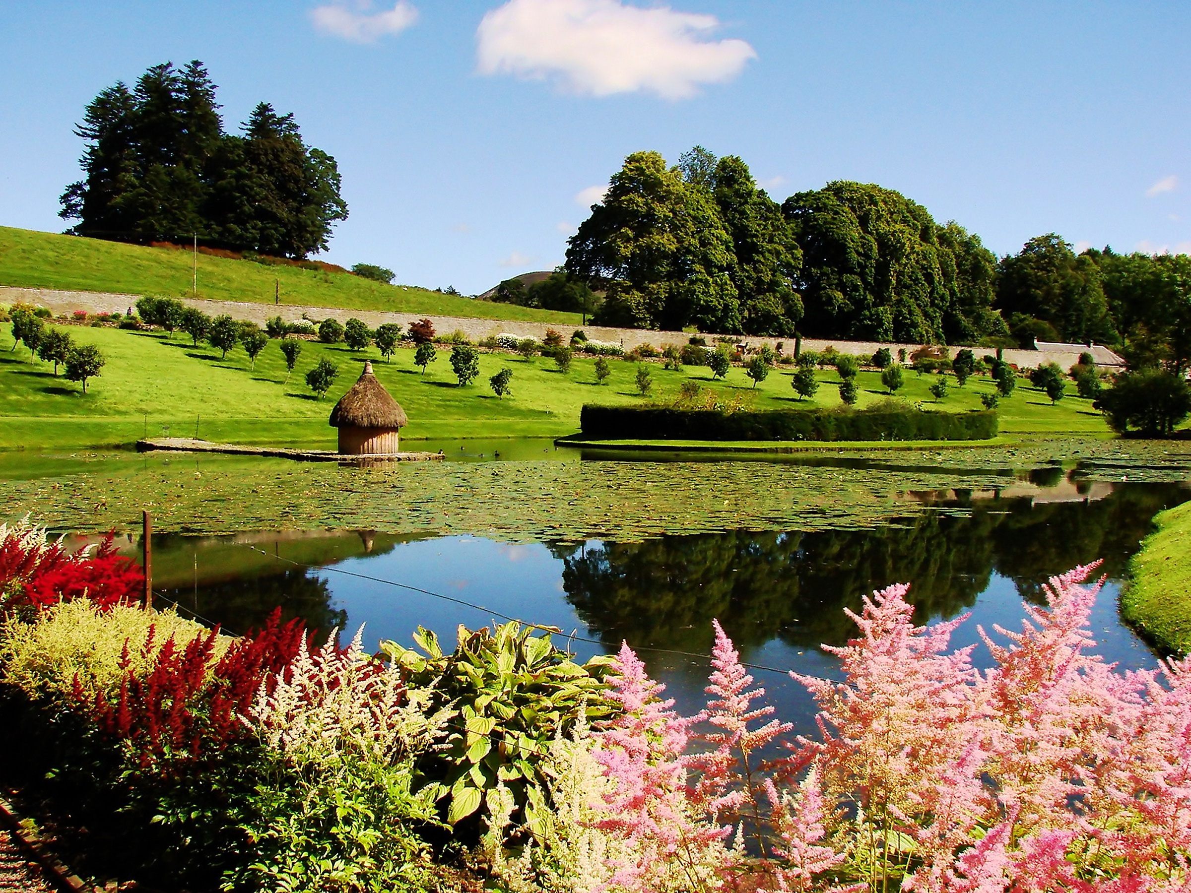 Den smukke Hercules Have med farverige blomster og spejlblankt vand ved Blair Castle i det historiske Skotland