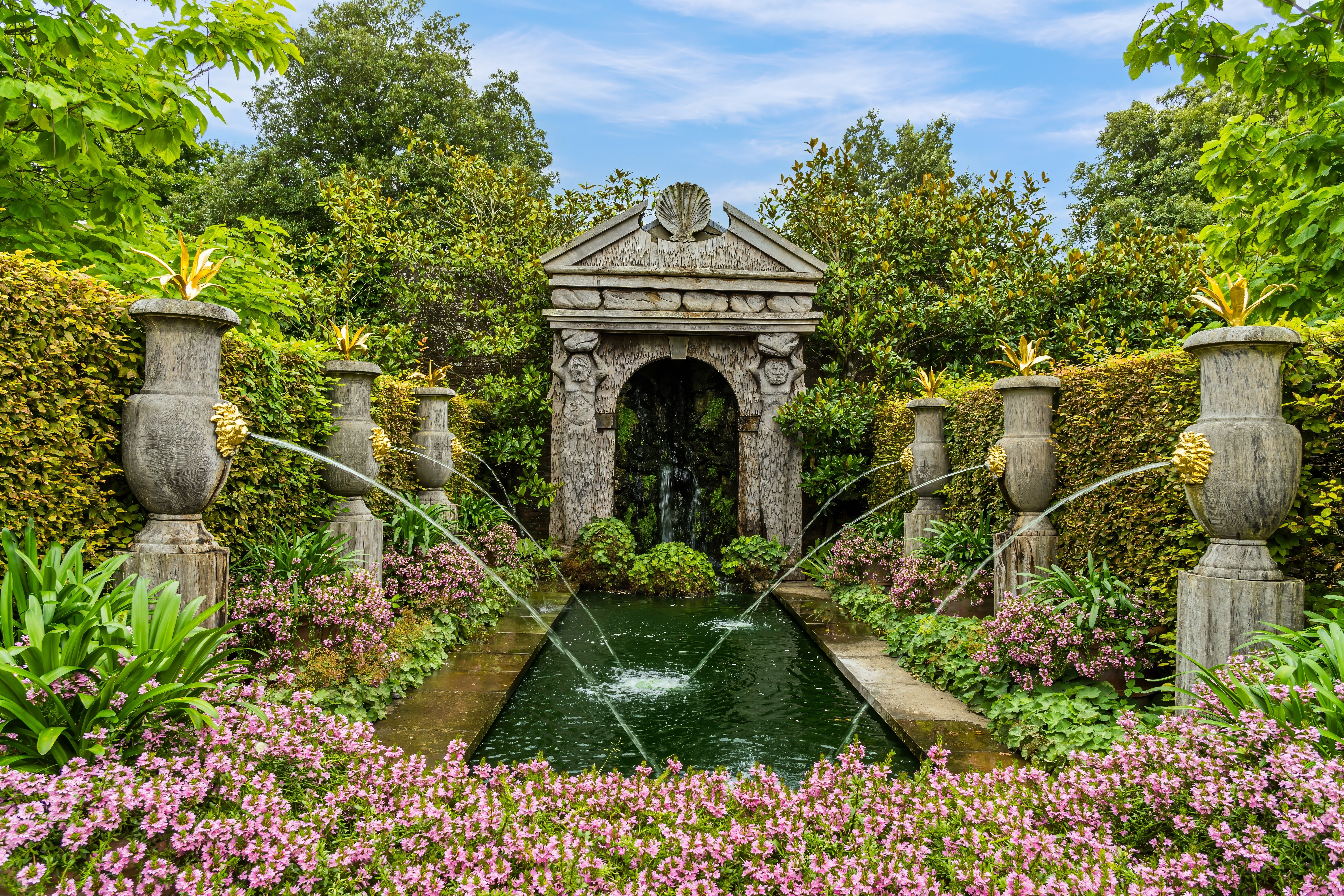 De smukke italienske haver ved Hever Castle i Kent, England, med klassisk stenbue, springvand og lyserøde blomster omgivet af grønne hække