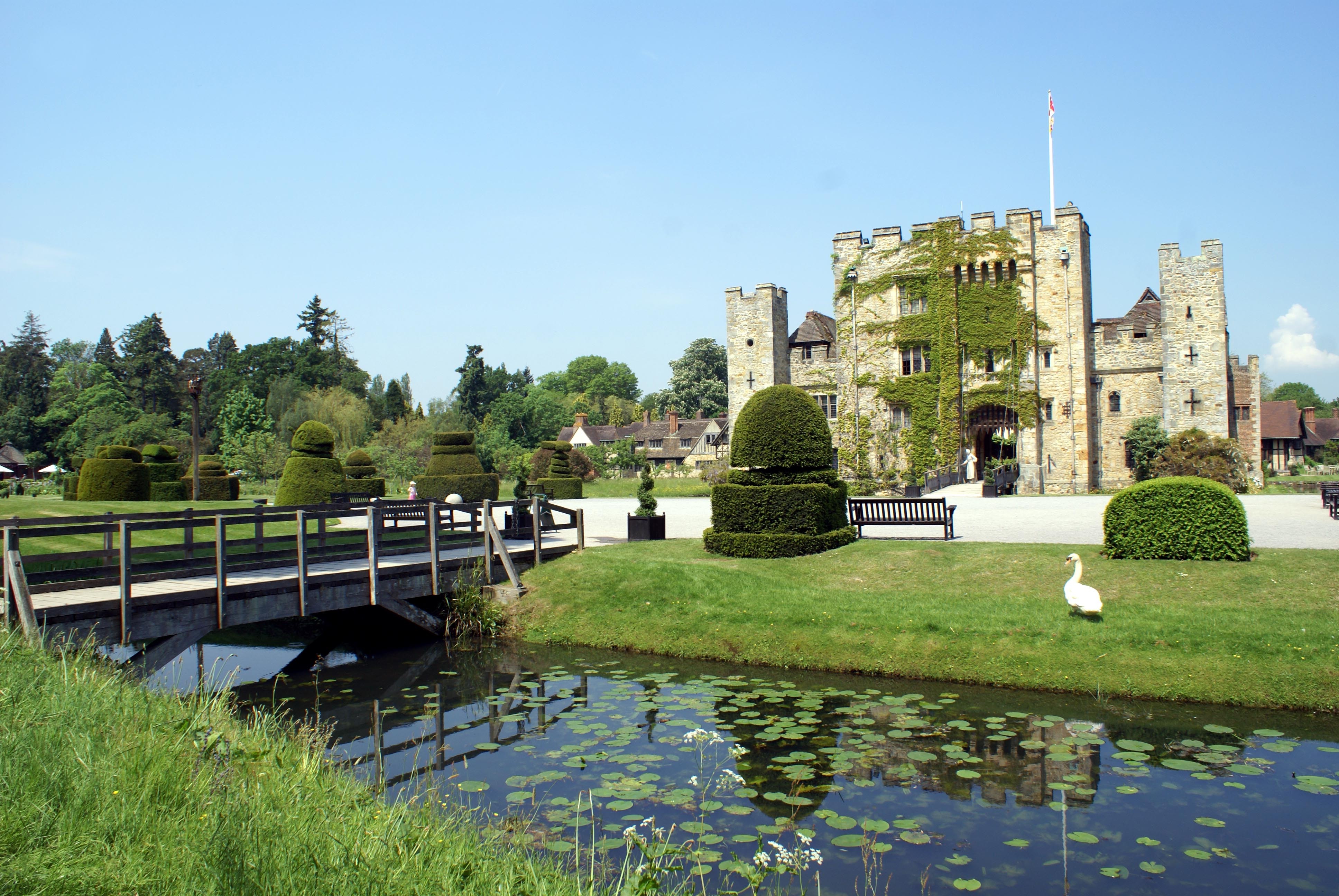 Hever Castle i Kent, England, med smukt formklippede hække, en brolagt voldgrav med åkander og en svane