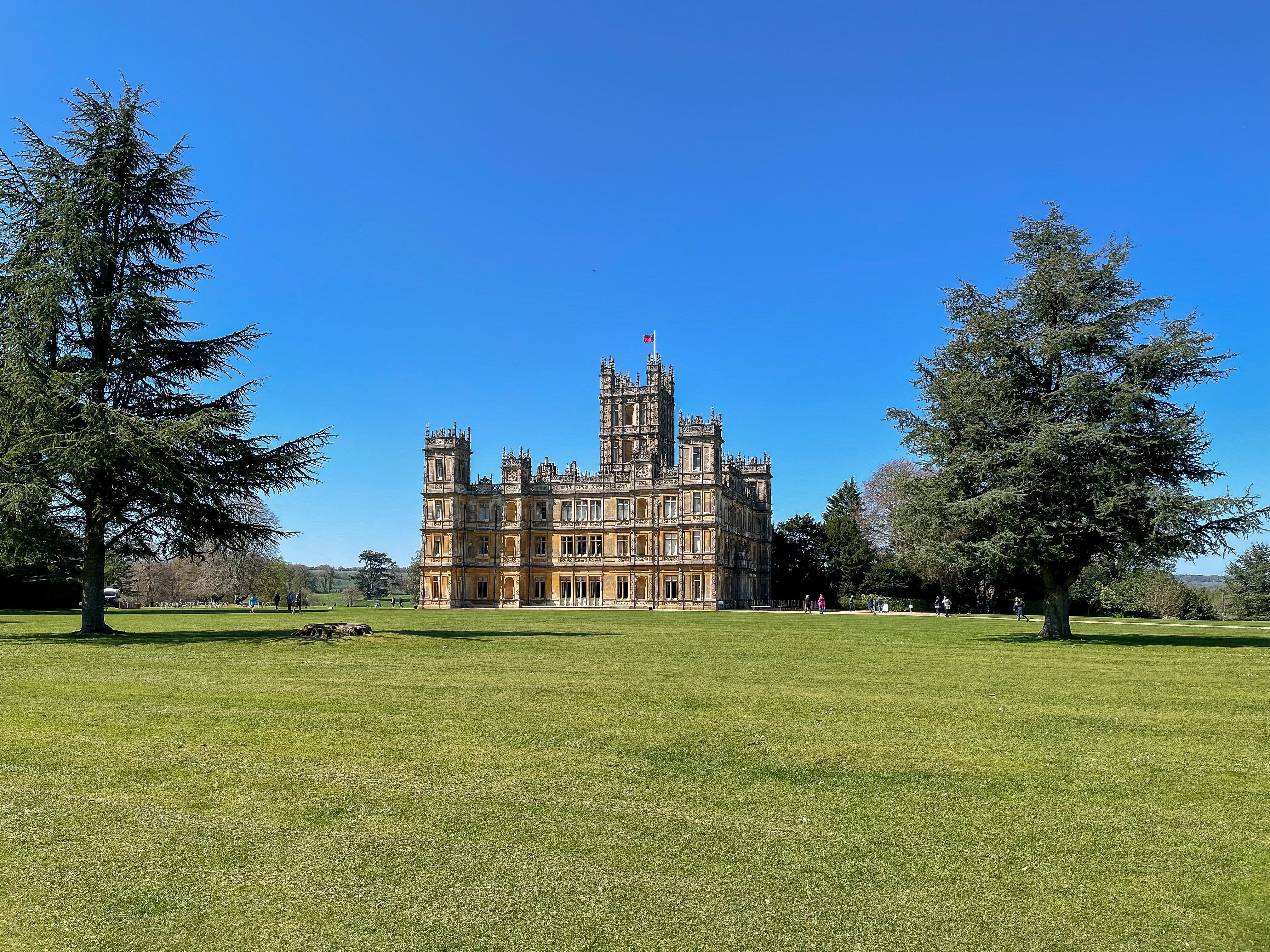 Highclere Castle omgivet af grønne græsarealer under blå himmel i Hampshire England