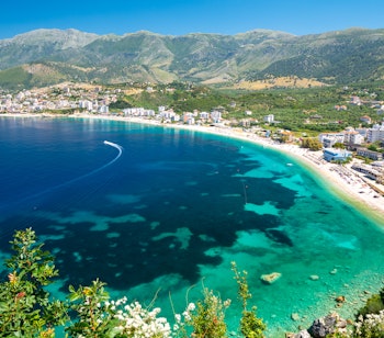 Betagende udsigt over Himare-bugten på den albanske riviera med krystalklart turkisblåt vand og dramatiske bjerge i baggrunden